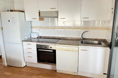 a white kitchen with a sink and a refrigerator at Apartment with sea views next to the beach of Mar Bella in Barcelona